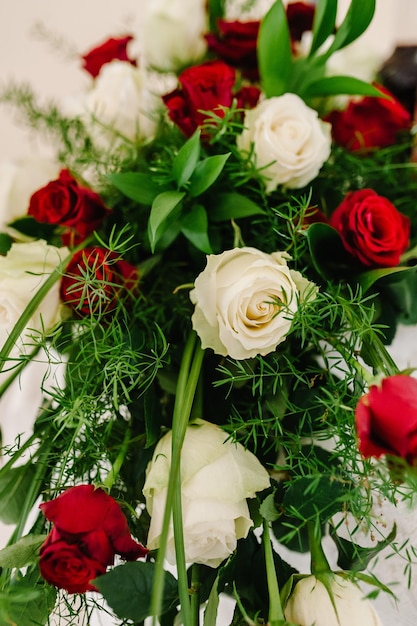 Buquê de rosas vermelhas e brancas decoradas com vegetação Um lindo buquê de flores da primavera na mesa Um lindo buquê de flores Fechar