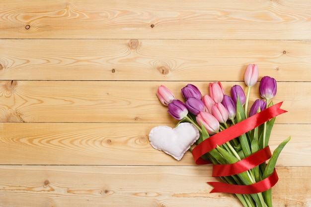 Buquê de tulipa com fita vermelha e coração de tecido artesanal em textura de madeira natural