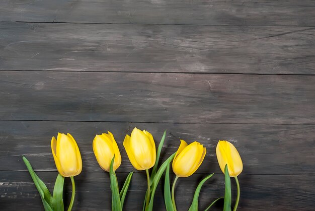 Buquê de tulipas amarelas com uma fita amarela em uma madeira