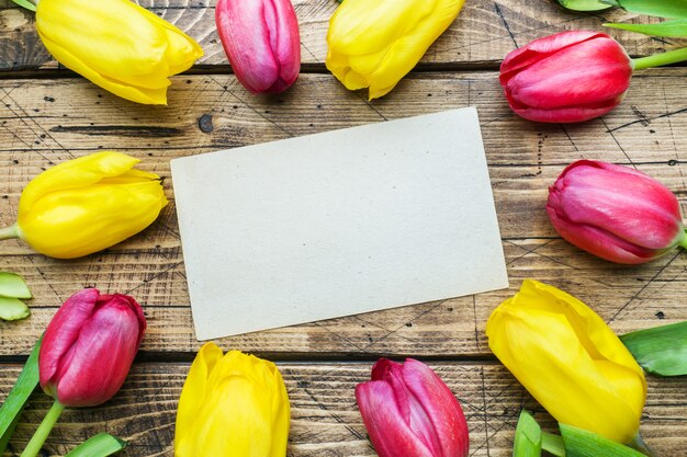 Buquê de tulipas amarelas e rosa em um fundo de madeira.