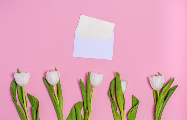 Foto buquê de tulipas brancas com um envelope e um cartão rosa