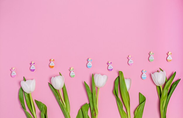 Buquê de tulipas brancas e prendedores de roupa decorativos em um fundo rosa, copie o espaço, configuração plana