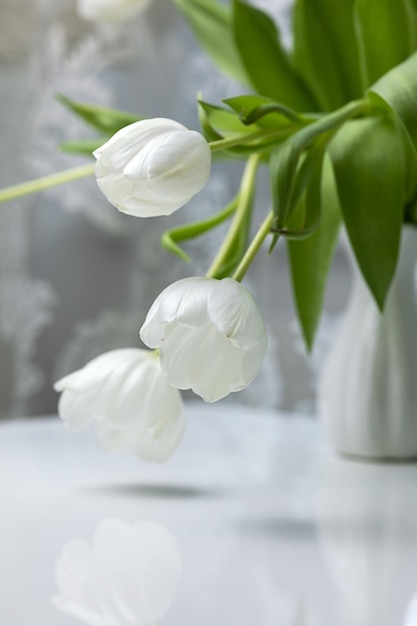 Buquê de tulipas brancas em um vaso branco em uma mesa branca