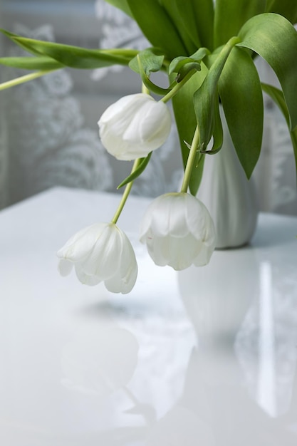 Buquê de tulipas brancas em um vaso branco em uma mesa branca