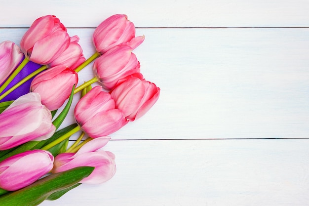 Buquê de tulipas cor de rosa com fita roxa no fundo branco