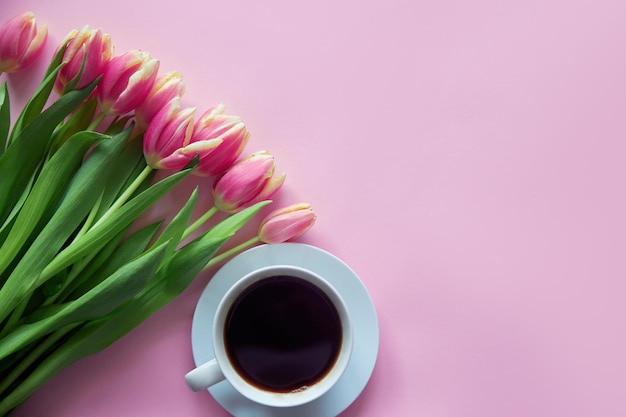Buquê de tulipas cor de rosa em fundo rosa com xícara de manhã dia das mães e mulheres