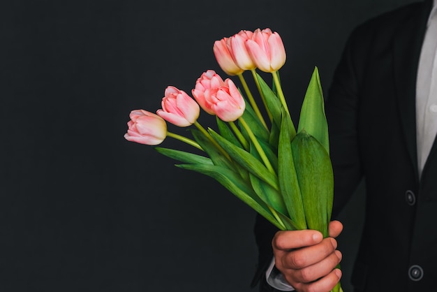 Buquê de tulipas cor de rosa nas mãos dos homens em um terno azul