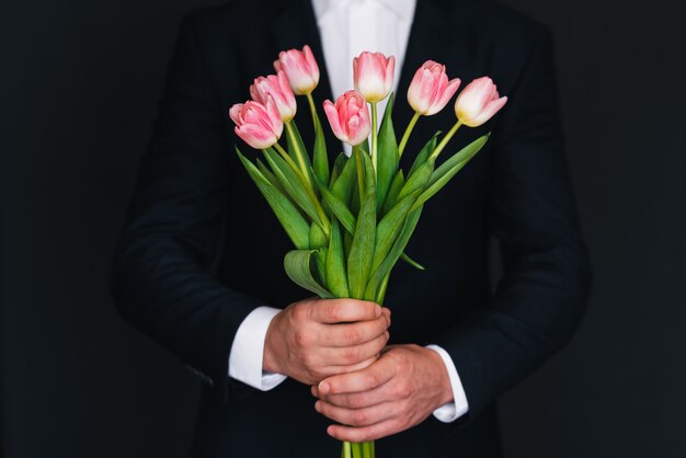 Buquê de tulipas cor de rosa nas mãos dos homens em um terno azul