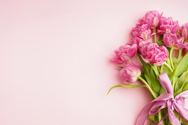 Foto buquê de tulipas de peônia rosa amarrado com um laço rosa no espaço de fundo rosa para o texto vista superior