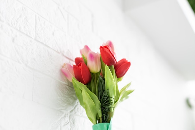 Buquê de tulipas de primavera com flores de cores diferentes embrulhadas em papel para presente em fundo branco.