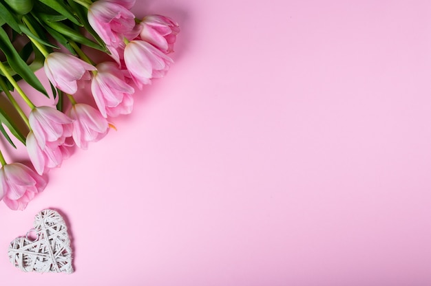 Buquê de tulipas e corações em fundo rosa. Vista de cima, estilo plano.