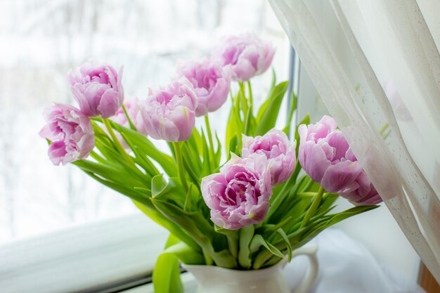 Buquê de tulipas lilás em um vaso na janela