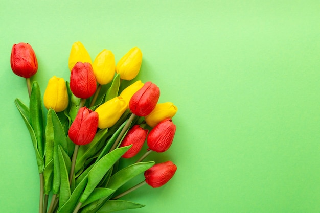 Buquê de tulipas vermelhas e amarelas sobre fundo verde. copie o espaço