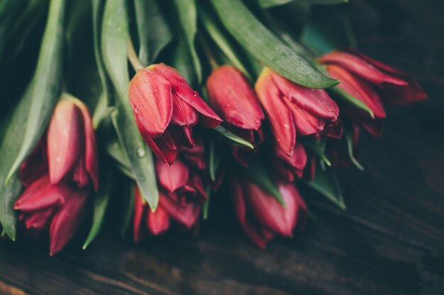 Buquê de tulipas vermelhas em uma mesa de madeira em um estilo escuro