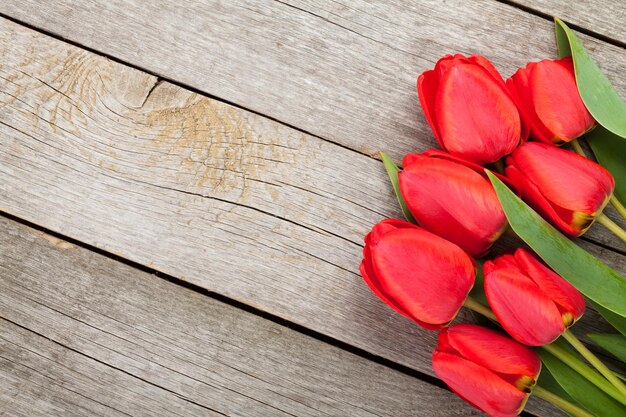 Buquê de tulipas vermelhas frescas sobre fundo de mesa de madeira