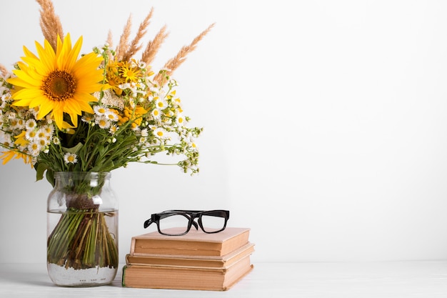 Buquê de verão de flores silvestres em vaso de vidro, livros antigos. Conceito de design de temporada. Conceito de dia de professores