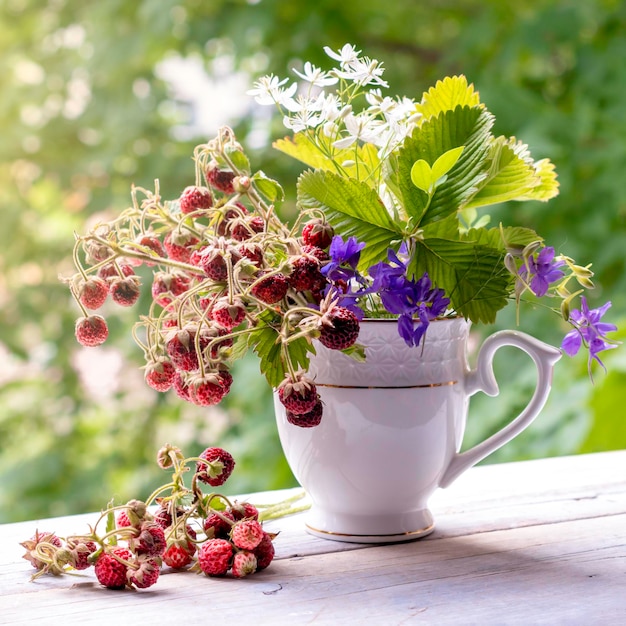 Buquê de verão de morangos silvestres e flores silvestres no peitoril da janela