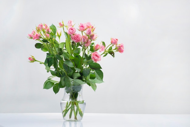 Buquê e buquê de rosas na água em um vaso de vidro isolado em um fundo branco