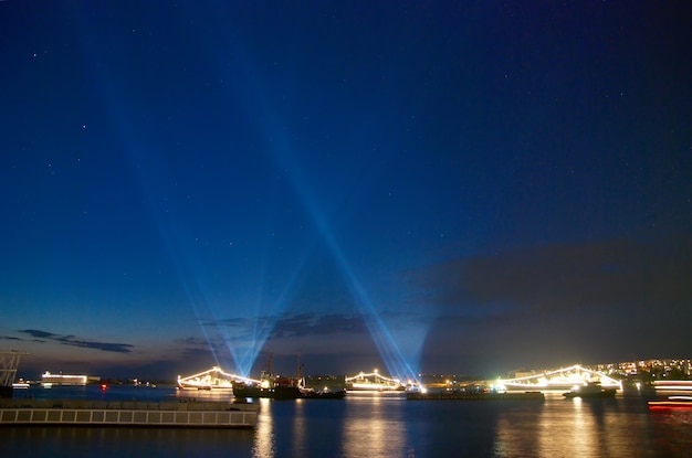 Buque de guerra iluminado y luz de vacaciones en la bahía de la noche del cielo