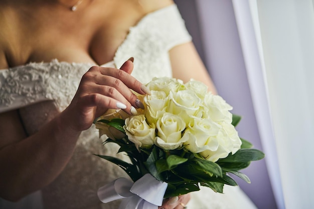 Buquê nas mãos da mulher noiva se preparando antes da cerimônia de casamento