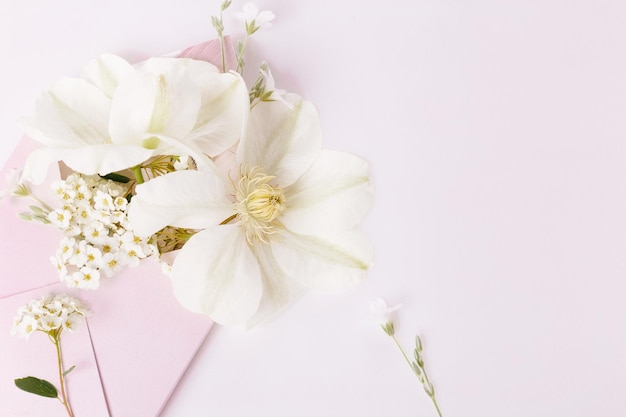 Buquê romântico de flores brancas de clematis em um envelope rosa vista de perto Vista superior plana lay Espaço de cópia Aniversário mães dia dos namorados conceito de dia do casamento
