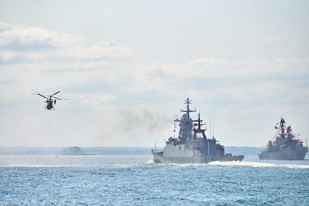 Buques de guerra acorazados corbeta durante ejercicios navales y maniobras de helicópteros sobre el agua en el Mar Báltico. Buques de guerra, helicópteros y barcos realizan tareas en el mar, buques de guerra militares navegando, Armada rusa