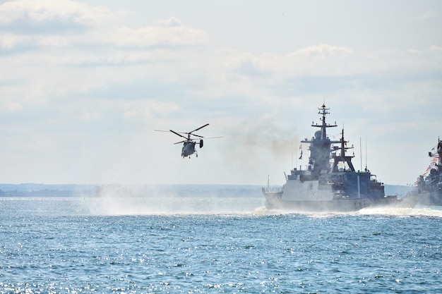 Buques de guerra acorazados corbeta durante ejercicios navales y maniobras de helicópteros sobre el agua en el Mar Báltico. Buques de guerra, helicópteros y barcos realizan tareas en el mar, buques de guerra militares navegando, Armada rusa