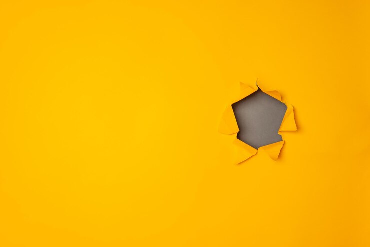 Foto buraco rasgado de papel grande em fundo amarelo com espaço de cópia.