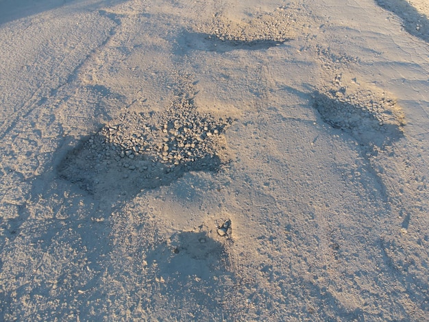 Buracos com poços na estrada danificada do asfalto velho