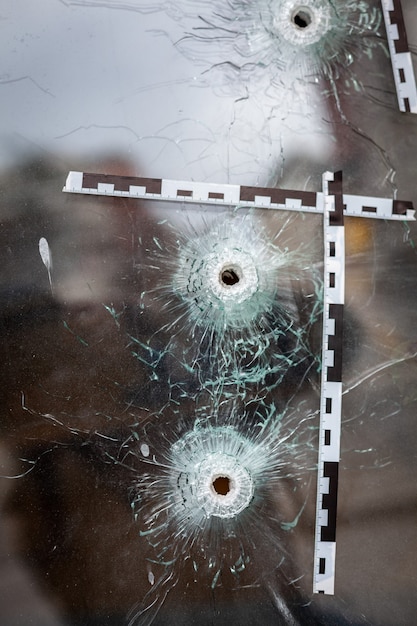 Foto buracos de bala na vitrine de uma loja de vidro marcados com fita isolante