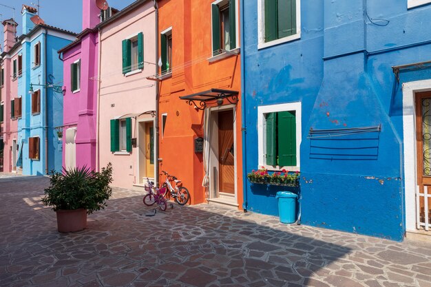Burano, Venecia, Italia - 02 de julio de 2018: Vista panorámica de casas de colores brillantes de Burano es una isla en la Laguna de Venecia. La gente camina y descansa en las calles. Día soleado de verano y cielo azul.