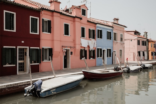 Burano, Venecia, Italia - 02 de julio de 2018: Vista panorámica de casas de colores brillantes y canal de agua con barcos en Burano, es una isla en la Laguna de Venecia. La gente camina y descansa en las calles.