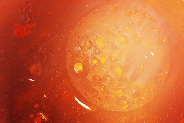 Las burbujas de aceite de oro cierran círculos de agua naranja y rosa macro abstracto fondo amarillo brillante