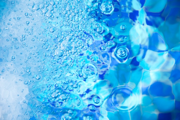 Burbujas de aire en el agua azul clara en la piscina para los fondos.