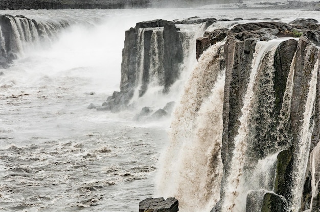 Las burbujeantes aguas turbias de la cascada de Selfoss bajo un cielo lluvioso gris Islandia