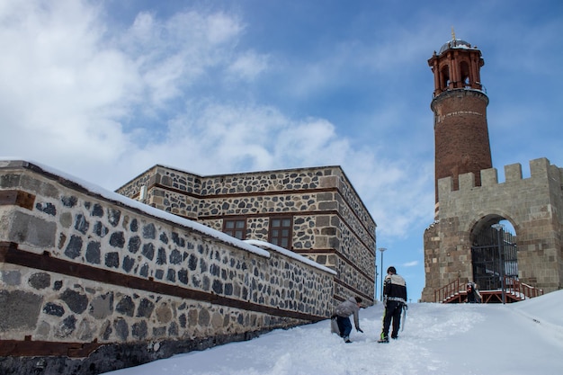 Burg Erzurum, Glockenturm, Winterlandschaft. Kinder rutschen im Schnee.