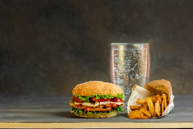 Burger auf einem rustikalen Holzbrett und arbonisiertes süßes Getränk in einem Glas