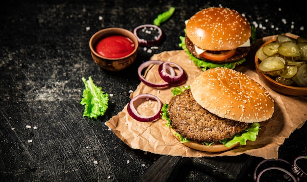 Burger auf einem Schneidbrett mit Zwiebeln, Tomatensauce und Salat