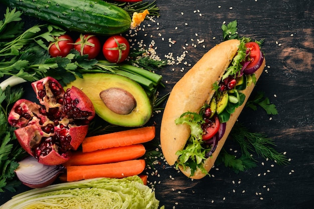 Burger-Avocado-Sandwich Kirschtomaten und Salatblätter auf einem hölzernen Hintergrund Draufsicht Kopierbereich