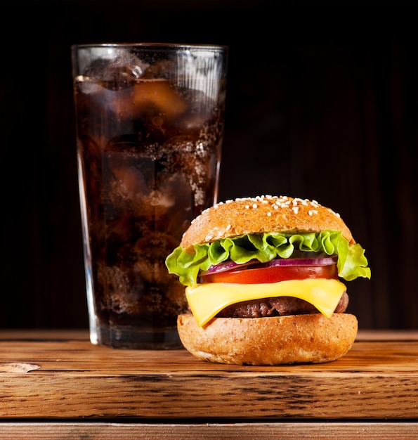 Burger-Cheeseburger mit Schnitzelkäse und Gemüse und einem Getränk mit Eis