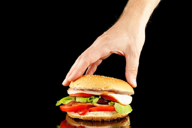 Burger in der Hand isolieren auf Schwarz