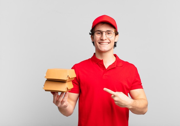 Burger liefern einen Jungen, der fröhlich lächelt, sich glücklich fühlt und zur Seite und nach oben zeigt und das Objekt im Kopierraum zeigt