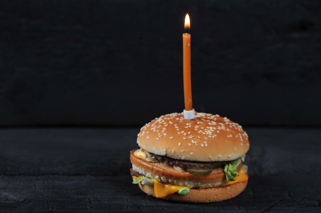 Burger mit einer Kerze mit Feuer