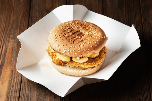 Burger mit Hühnchen und knusprigen Maissnacks schließen hautnah in der Papierlieferbox