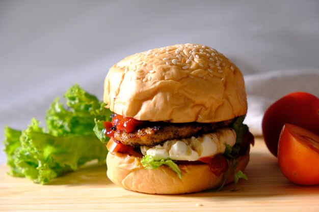 Burger mit Käse, Salaten und Gemüse auf einem weißen Raum