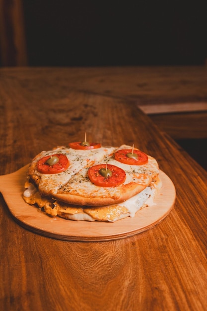 Foto burger mit pizza-top auf einem holz-tisch-vertikalbild