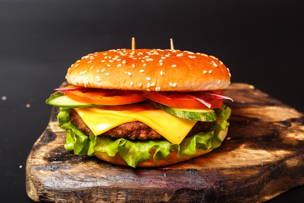 Burger mit Rind- und Hühnerschnitzel auf einem Holzbrett mit isoliertem schwarzem Hintergrund