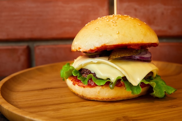 Burger mit Rindfleisch, Käse und Salatblättern auf einem Holzteller