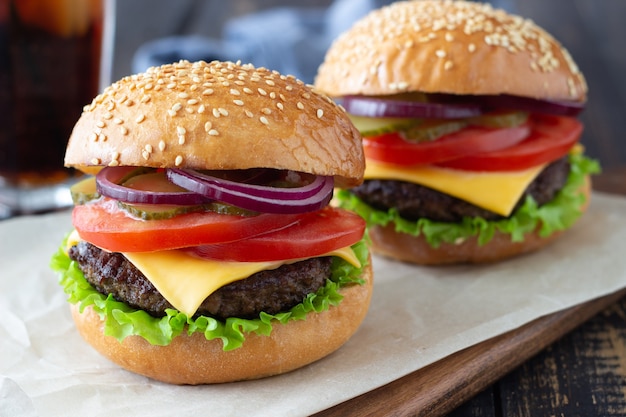 Burger mit Schnitzel, Tomate, Salat, Gurke, Zwiebel und Käse. Amerikanische Küche. Fast Food. Cheeseburger.