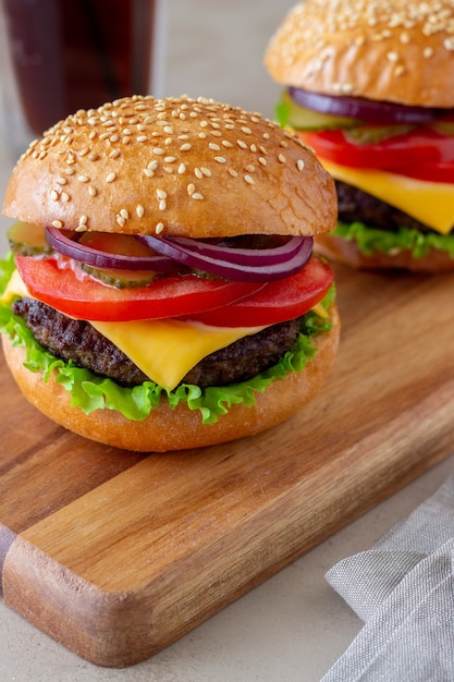 Burger mit Schnitzel, Tomate, Salat, Gurke, Zwiebel und Käse. Amerikanische Küche. Fast Food. Cheeseburger.